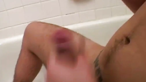 Dirty Tyler sits in the tub and starts jerking his thick uncut cock